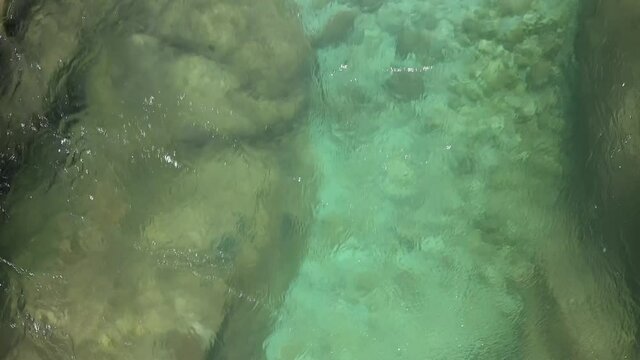 Drone follows the flowing water of a clear green river in Slovenia