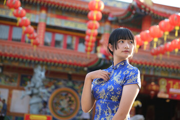 beauty woman wear red cheongsam looking and smile in chinese new year