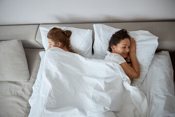 Obraz na płótnie Canvas Two delighted women lying together under soft blanket