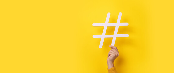 hand showing HASHTAG over yellow background, business concept, panoramic mock-up