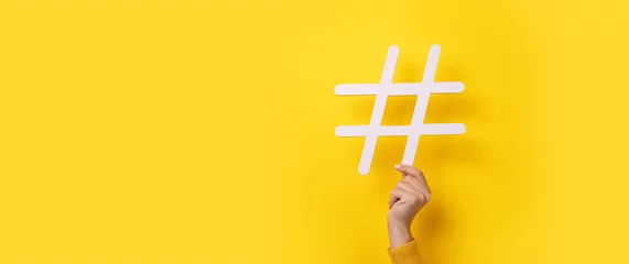 Fotobehang hand showing HASHTAG over yellow background, business concept, panoramic mock-up © alesmunt