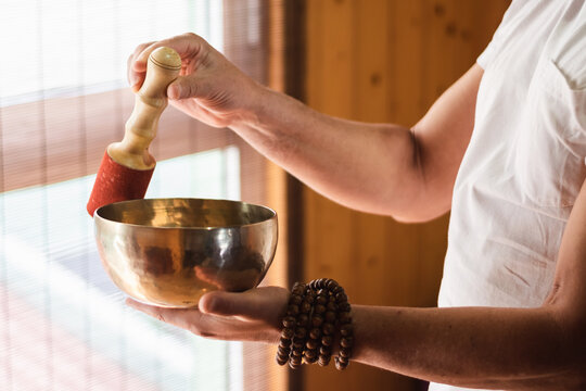 Man with a mala holding and playing a Tibetan bowl