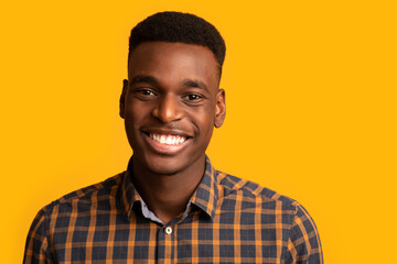 Closeup portrait of positive young African American guy sincerely smiling at camera