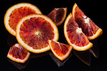 Red sicilian orange fruit slices on black reflective background. Fresh, ripe bloody orange wallpaper
