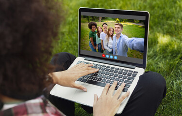 Fototapeta na wymiar Unrecognizable young guy having video call with group of friends on laptop at park