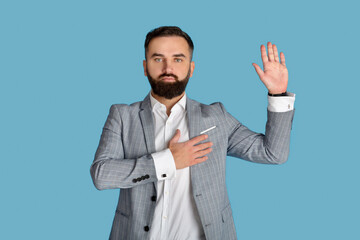 Portrait of serious young congressman taking oath on blue studio background