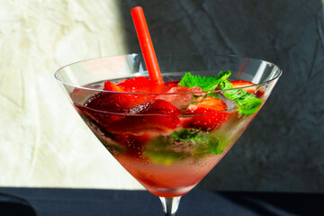  cooling strawberry cocktail with ice and mint on black and concrete background, stylish and tasty, unusual martini