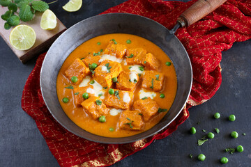 Matar Paneer curry, paneer butter masala recipe made using cottage cheese, green peas, served in a bowl.  Delhi, Rajasthan India. Indian veg curry wooden background. side dish of Roti, Chapati, naan