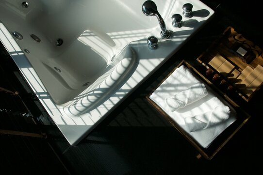 Light and shadow on the granite floor and Warm lighting in spa resort, Close up of spa essentials and towels on wooden tray in bathroom, essential oil. Spa products set conception.