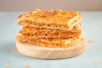 Closeup of stacked portions of an empanada with natural ingredients such a tomato, onion, pepper, tuna, egg and dough of wheat on a wooden plate. Tuna pie. Typical Galician dish from Galicia and Spain