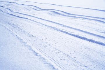 Rolled winter country road with a snow car tracks.