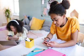 Portrait of young sisters indoors at home, using smartphone.