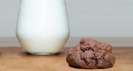 chocolate chip cookies and a glass of milk on wooden background, front view