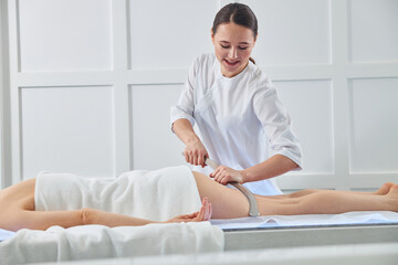 Obraz na płótnie Canvas Concentrated massagist placing gua sha tool on back of hip