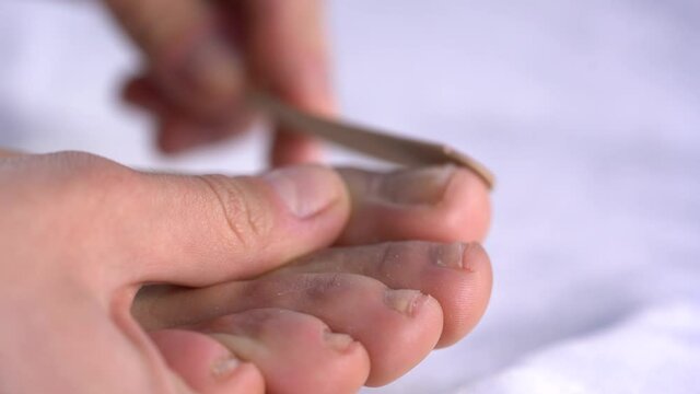 close up of woman filling her toe nails on white background