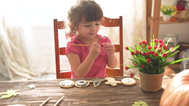 Little girl painting halloween cookies