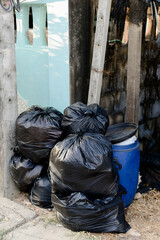 Pile of black plastic trash bags, bulk trash bags on footpaths, pollution bins.