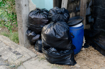 Pile of black plastic trash bags, bulk trash bags on footpaths, pollution bins.