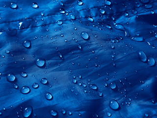 Water drops on waterproof membrane fabric. Detail view of texture of blue waterproof cloth.