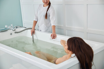 Woman with loose hair relaxing in tub during whirlpool massage