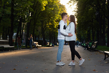 Fototapeta premium Happy young couple kissing in park. Full size portrait. First date