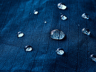 Water drops on waterproof membrane fabric. Detail view of texture of blue waterproof cloth.