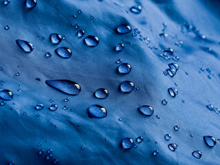 Water drops on waterproof membrane fabric. Detail view of texture of blue waterproof cloth.
