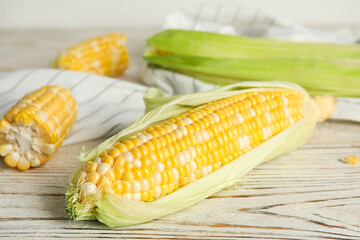 Tasty sweet corn cobs on white wooden table, closeup