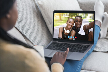 Digital communication concept. Young lady having video call with happy black couple on laptop from home