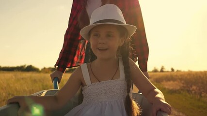A teenage girl rides her little sister on a garden cart. Children play farmer. The kids are happy.