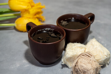 Two cups of tea or coffee with Traditional Turkish cotton candy (Pismaniye). Tea, yellow tulips on a gray background. Close-up