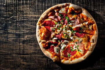Round pizza on a wooden board. Copy space and free space for text near food. contrasting dramatic light as an artistic effect.