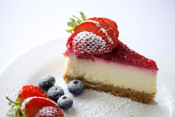 Strawberry cheesecake decorated with strawberries and blueberries and icing sugar