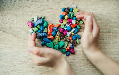 children's hands are holding colorful pebbles