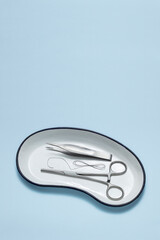Set of sutures,silk thread for suturing, forceps, scissors, in medical tray on blue background
