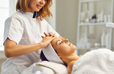 Obraz na płótnie Canvas Cosmetologist or dermatologist making facial beauty massage treatment for young woman in beauty spa salon with fingers