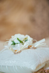 Obraz na płótnie Canvas Wedding rings lie on a beautiful, decorative hand made pillow , copy space