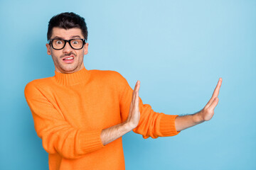 Portrait of worried handsome guy show hands palms reject gesture empty space isolated on blue color...