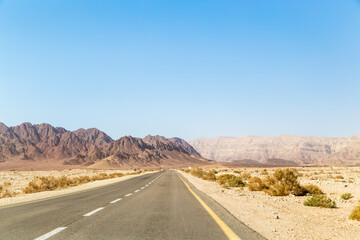 Fototapeta na wymiar Road in desert leading up to the mountains Timna open empty road. Timna National Park.