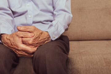 Unrecognizable caucasian old man sitting on sofa.