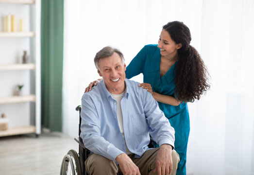 Portrait of happy impaired elderly man and his female nurse at retirement home. Professional medical care for seniors