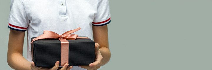 Male hands holding a gift box. Present wrapped with ribbon and bow. Christmas or birthday package. Man in white shirt. Place for your text or design.