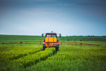 Fototapeta premium Farming tractor plowing and spraying on field