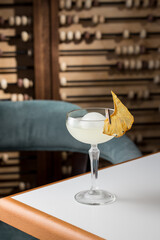 margarita glass cocktail with ice ball and dried pineapple on the table at restaurant