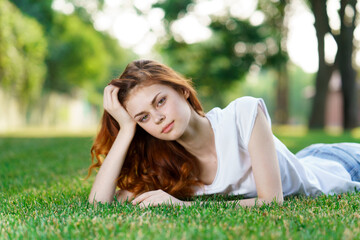 Naklejka na ściany i meble woman lies on the grass in the park outdoors charm leisure nature