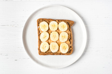 Homemade peanut butter sandwich with bananas and honey on wooden background.