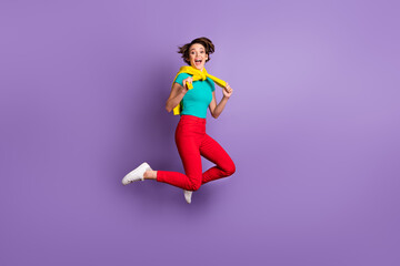 Fototapeta na wymiar Full length photo of lady jump open mouth wear tied pullover t-shirt trousers sneakers isolated purple color background