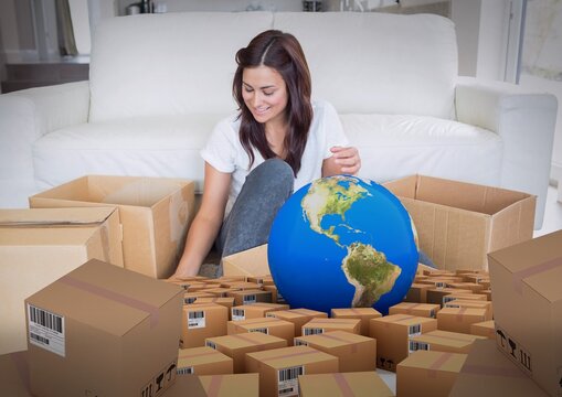Composition of globe and cardboard boxes with woman unpacking in new home
