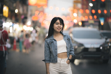 Fototapeta premium Beautiful Asian woman who has long hair travels to the festival at Yaowarat Chinatown in Thailand. Street photography of traveler woman at night.