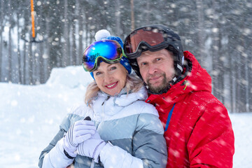 Fototapeta na wymiar Portrait of a smiling happy mature couple, in ski clothing at a ski resort. Healthy lifestyle, winter outdoor activity.